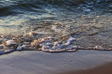 Dalgalar büyük bir nehir kıyısında kumlu. Işık ışınları dalgalar halinde yansıtılır,