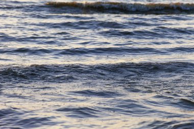 Dalgalar büyük bir nehir kıyısında kumlu. Işık ışınları dalgalar halinde yansıtılır,