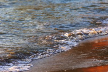 Dalgalar büyük bir nehir kıyısında kumlu. Işık ışınları dalgalar halinde yansıtılır,