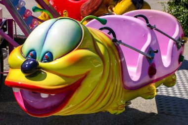 Carousel bir eğlence parkı bir tırtıl şeklinde. Çocuklar için eğlence. Çok renkli Işık Ampüller. Akşam gökyüzü.