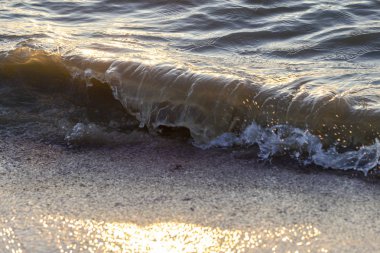 Dalgalar büyük bir nehir kıyısında kumlu. Işık ışınları dalgalar halinde yansıtılır,