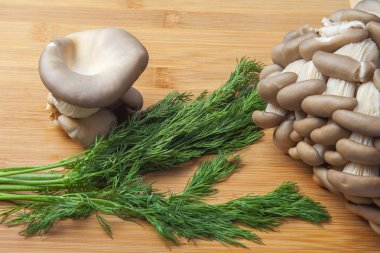 Taze istiridye mantar kümeleri doğal bir bambu kesme tahtası üzerine serilmiş.