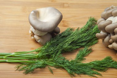 Taze istiridye mantar kümeleri doğal bir bambu kesme tahtası üzerine serilmiş.