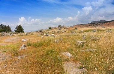 Dağlık arazide açık çimenli kırsalda harap binaların taş kalıntıları