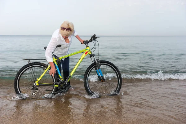 Mujer Pie Sus Pantalones Vaqueros Oleaje Inclinándose Para Comprobar Bicicleta —  Fotos de Stock