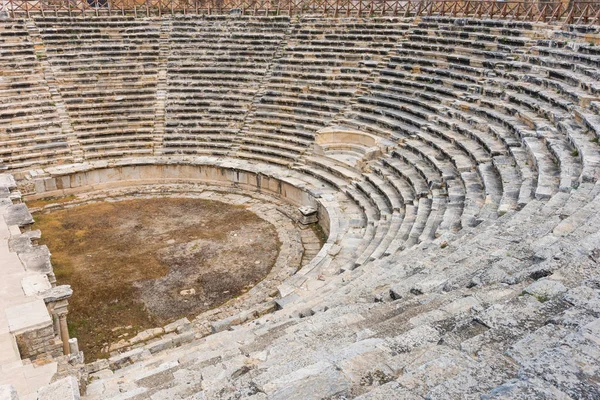 Circular stone seating in a well preserved Greek amphitheatre viewed looking down from the top to the arena
