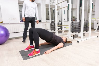 Spor salonunda mat yatarken bacaklar egzersiz sırasında kalça yükselterek kadın