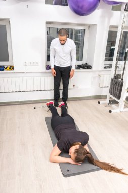 Kadın spor salonunda eğitmenle egzersiz yapıyor.