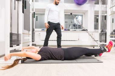 Spor salonunda mat yatarken ayak kablo makine üzerinde egzersiz kadın