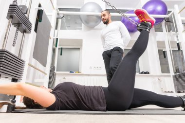 Genç kadın eğitim ayak kablo crossover makine spor hocası ile üzerinde