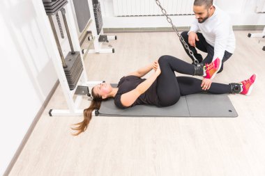Spor salonunda kişisel antrenör ile kablo crossover makinede egzersiz kadın