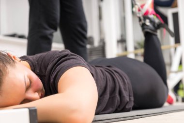 Genç kadın spor salonunda egzersiz bacak zam makine kullanarak yalan.