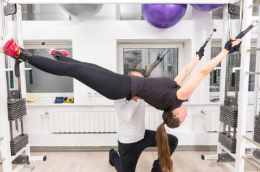 Spor hocası ile kablo crossover makinede uzanan kadın
