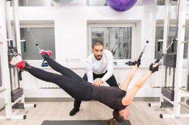 Kadının kablo makine vasıl jimnastik salonu ile kişisel antrenör asılı yapması