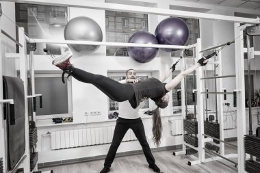 Onun yanında duran eğitmen ile fiziksel egzersiz için siyah kayışları ile düzenlenen kadının siyah beyaz filtresini kullanarak görüntü