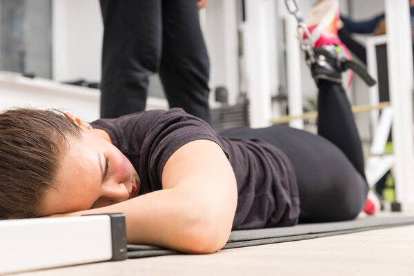 Young woman exercising legs with weights machine during workout.