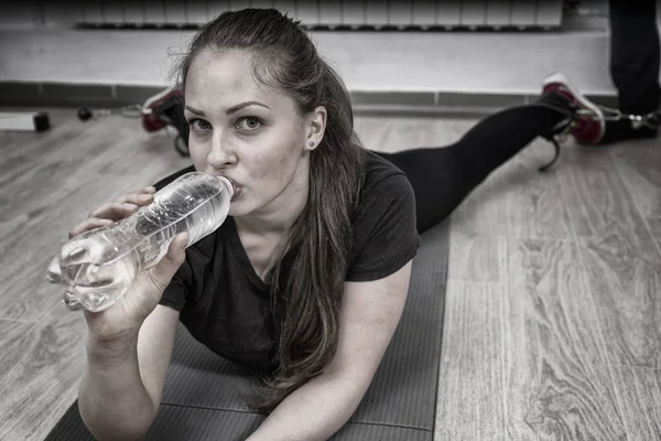 Frau Trinkt Wasser Während Sie Fitnessstudio Auf Matte Liegt — Stockfoto