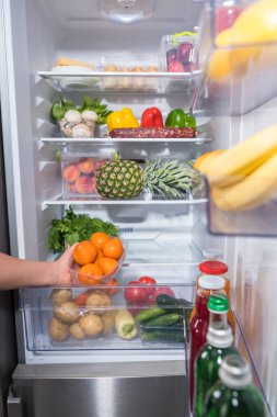 Taze portakal ile Plastik Konteyner buzdolabından alarak kişi