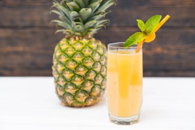 Ananas meyve ve bardak saman ahşap arka plan ile taze meyve suyu