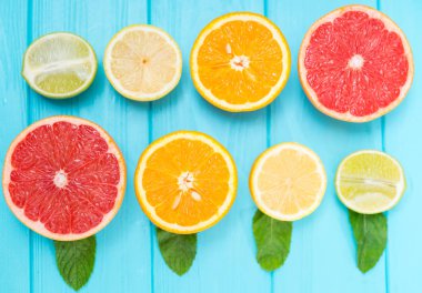 Natürmort, çeşitli yönleri ile limon, limon, portakal ve ruby greyfurt mavi bir arka plan üzerinde alternatif olarak iki satır Taze narenciye meyve yarıya