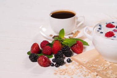 Çeşitli taze çilek, yaban mersini, böğürtlen, ahududu ve çilek, kahve ve süt ile tahıl ile kahvaltı masasında da dahil olmak üzere
