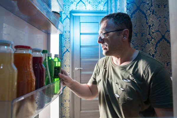 カジュアルなオヤジから冷蔵庫内のビュー ポイントと冷蔵庫のドアに飲料のボトルを検索 — ストック写真