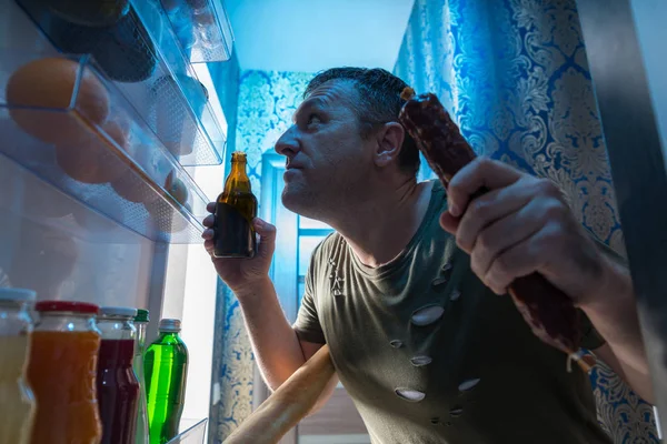 Hombre Hambriento Seleccionando Comida Una Nevera Pie Sosteniendo Salami Entero —  Fotos de Stock