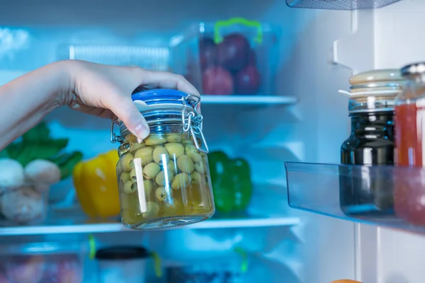 Persona Possesso Vaso Con Olive Verdi Contro Frigorifero Aperto — Foto Stock