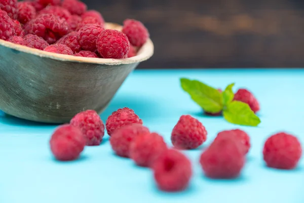 Tigela Framboesas Frescas Com Frutas Espalhadas Contra Mesa Azul — Fotografia de Stock