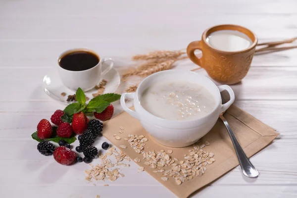Oatmeal porridge with fruits and cup of coffee on breakfast table