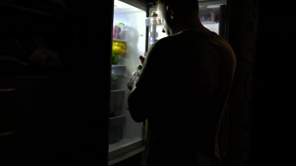Un uomo assetato apre la porta del frigo di notte — Video Stock