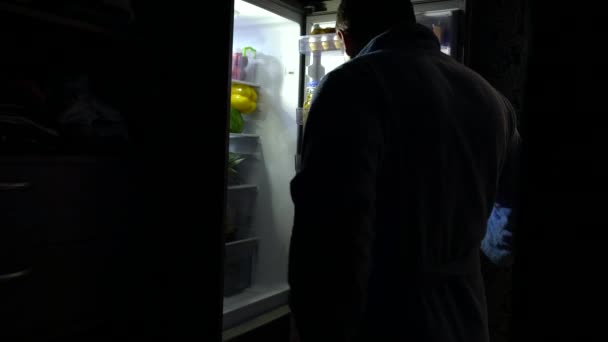 Adam gece yarısı bir buzdolabı açılış — Stok video