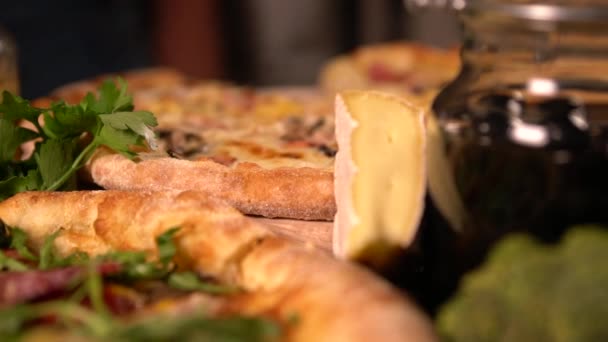 Meerdere verschillende pizza's naast potten van olijven — Stockvideo