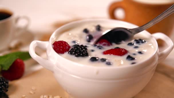 人舀一碗燕麦粥与各种各样的新鲜浆果和牛奶为健康早餐 — 图库视频影像