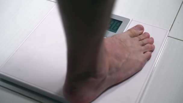 Hombre con los pies desnudos pesándose en una balanza — Vídeos de Stock