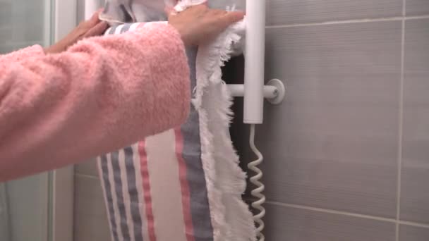 Woman in a pink dressing gown hanging a towel — Stock Video