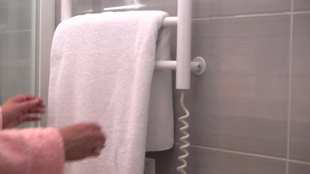 Woman removing a clean white towel of a rail — Stock Video