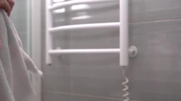 Person im Bademantel schüttelt ein Handtuch — Stockvideo