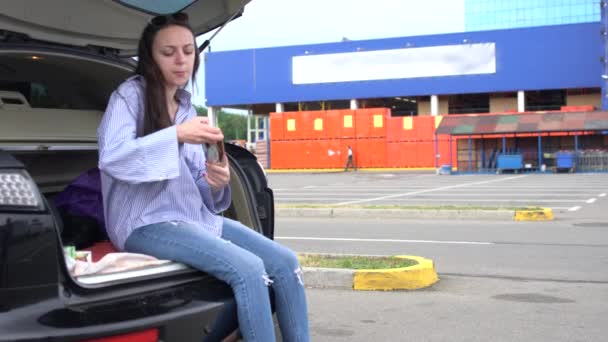 Femme assise dans le coffre ouvert de l'automobile — Video