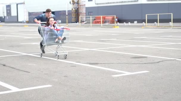 Man pushing female friend in shopping cart — Stock Video