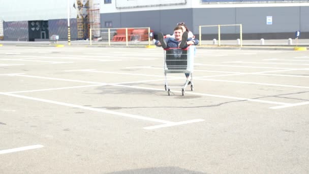 Pareja joven jugando con un carrito de compras — Vídeo de stock