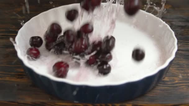 Cerejas vermelhas maduras molhadas sendo derramadas em uma tigela — Vídeo de Stock