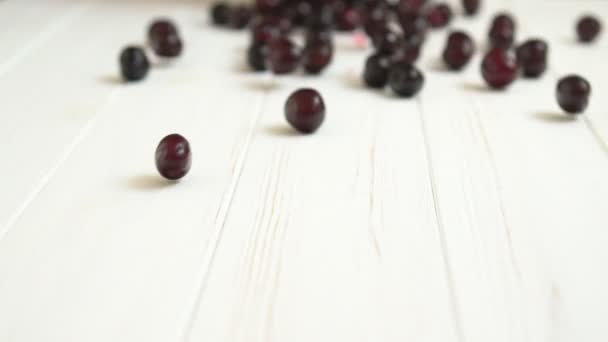 Ripe cherries rolling across a wooden table — Stock Video