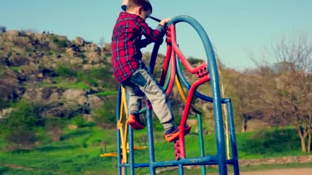 Niño jugando en un patio de recreo — Vídeos de Stock