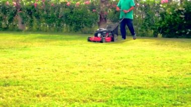 Adam kırmızı çim biçme makinesi ile çim biçme