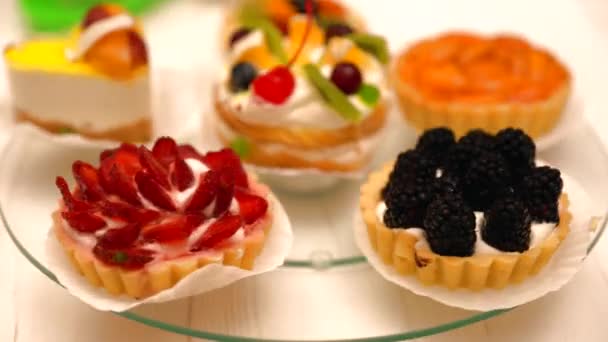 Assorted fresh fruit pastries spinning on glass — Stock Video