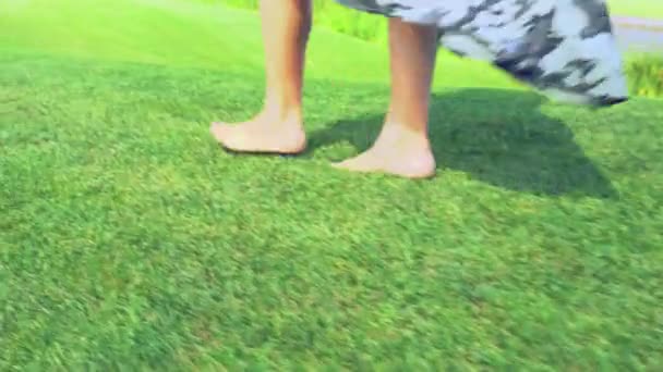 Woman walking bare foot across green grass — Stock Video