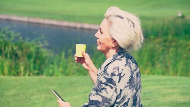 Starší blond žena stojící pití kávy — Stock video
