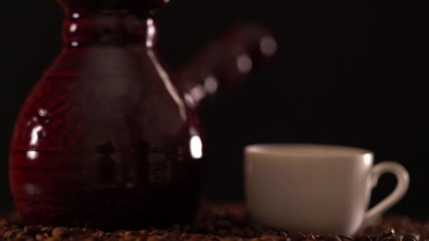 Low angle of a white cup and pot on coffee beans — Stock Video