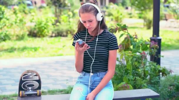 Κορίτσι που κάθεται στον πάγκο, ενώ ακούτε μουσική — Αρχείο Βίντεο